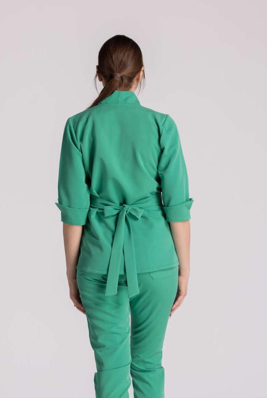 Bluza Medicala Elastica Elise - femeie îmbrăcată în bluza medicală verde, cu spatele la cameră, detaliu cu fundă